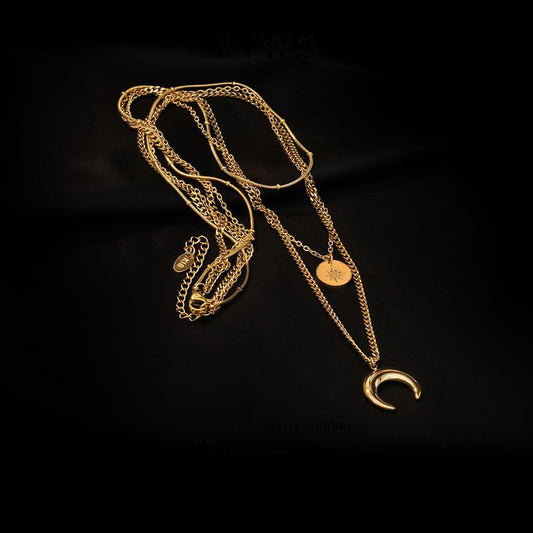 Flat lay of the triple-layer gold necklace showing the lobster clasp, extender chain, and high-polish pendants.
