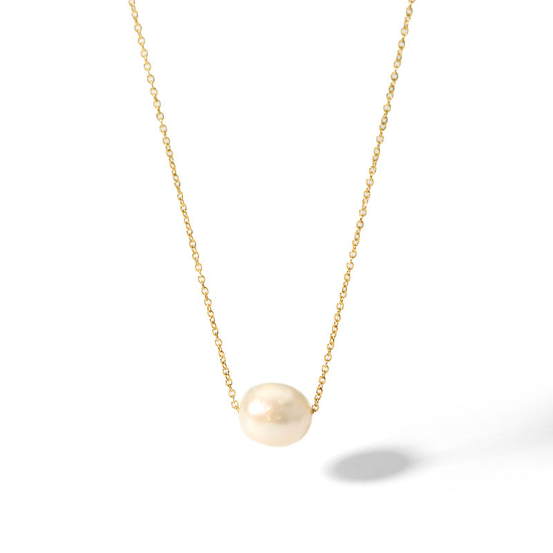 A floating baroque freshwater pearl on a delicate 18K gold plated cable chain isolated on a white background.