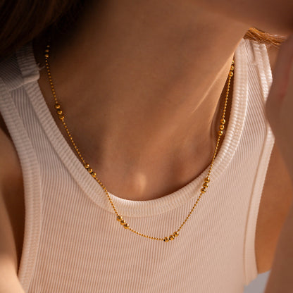 A model wearing the gold-plated bead necklace styled with a white ribbed tank top for a casual "IG Style" look.