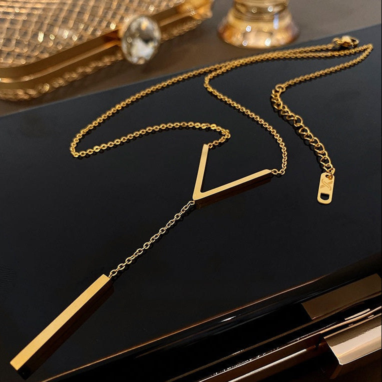 Aesthetic flat lay of the non-tarnish gold lariat necklace resting on a polished black surface, displaying the lobster clasp and adjustable 5cm extender.
