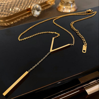 Aesthetic flat lay of the non-tarnish gold lariat necklace resting on a polished black surface, displaying the lobster clasp and adjustable 5cm extender.