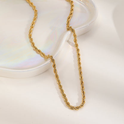 Aesthetic shot of a gold-plated 304 stainless steel rope chain draped over a white iridescent decorative heart-shaped tray.