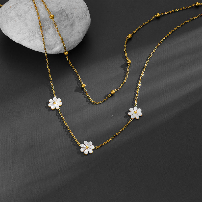 Aesthetic shot of the tarnish-free gold floral necklace draped over a gray stone, showcasing the delicate cable chain.