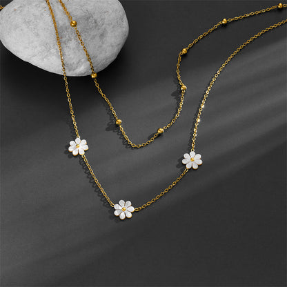 Aesthetic shot of the tarnish-free gold floral necklace draped over a gray stone, showcasing the delicate cable chain.