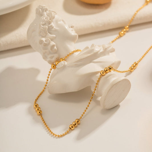 Artistic display of the gold stainless steel necklace draped over a white Greek-style bust sculpture.
