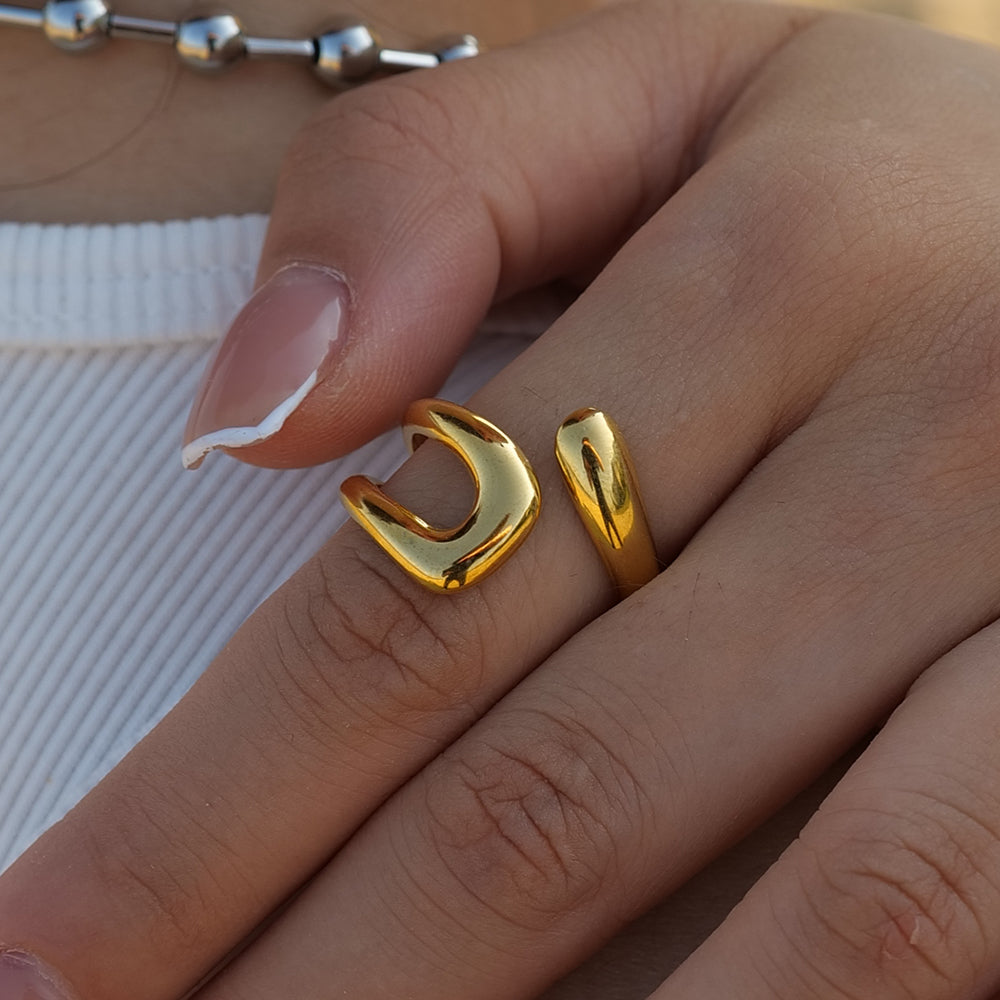 Close-up detail of the 18K gold PVD coated ring on a model's hand, highlighting the high-polish irregular texture.