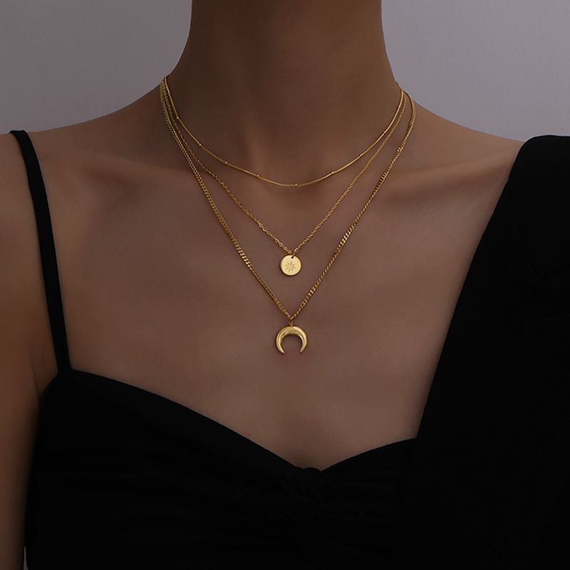 Close-up of the 18K gold plated moon and star necklace pendants on a model's neckline.