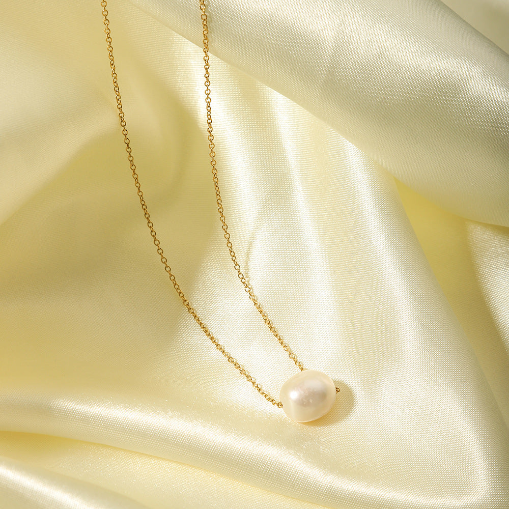 Close-up of the shimmering freshwater pearl pendant resting on luxurious yellow-gold silk fabric.