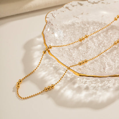 Close-up of the tarnish-free gold chain necklace resting on a textured decorative glass plate.