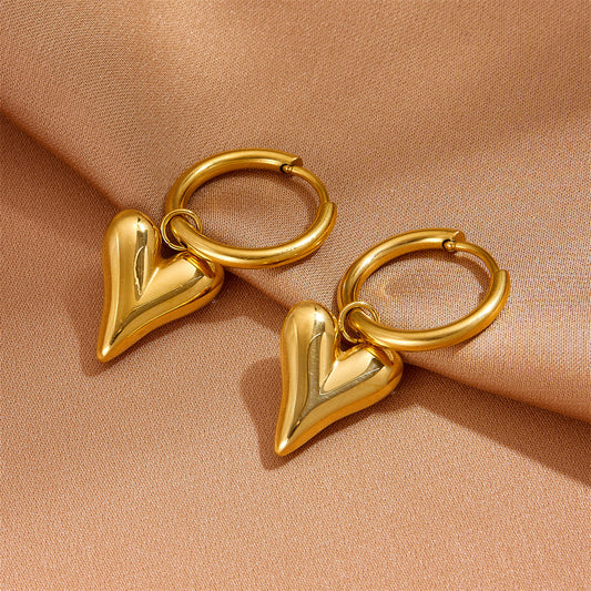 Close-up of the waterproof gold heart earrings showing the secure click-hoop closure.