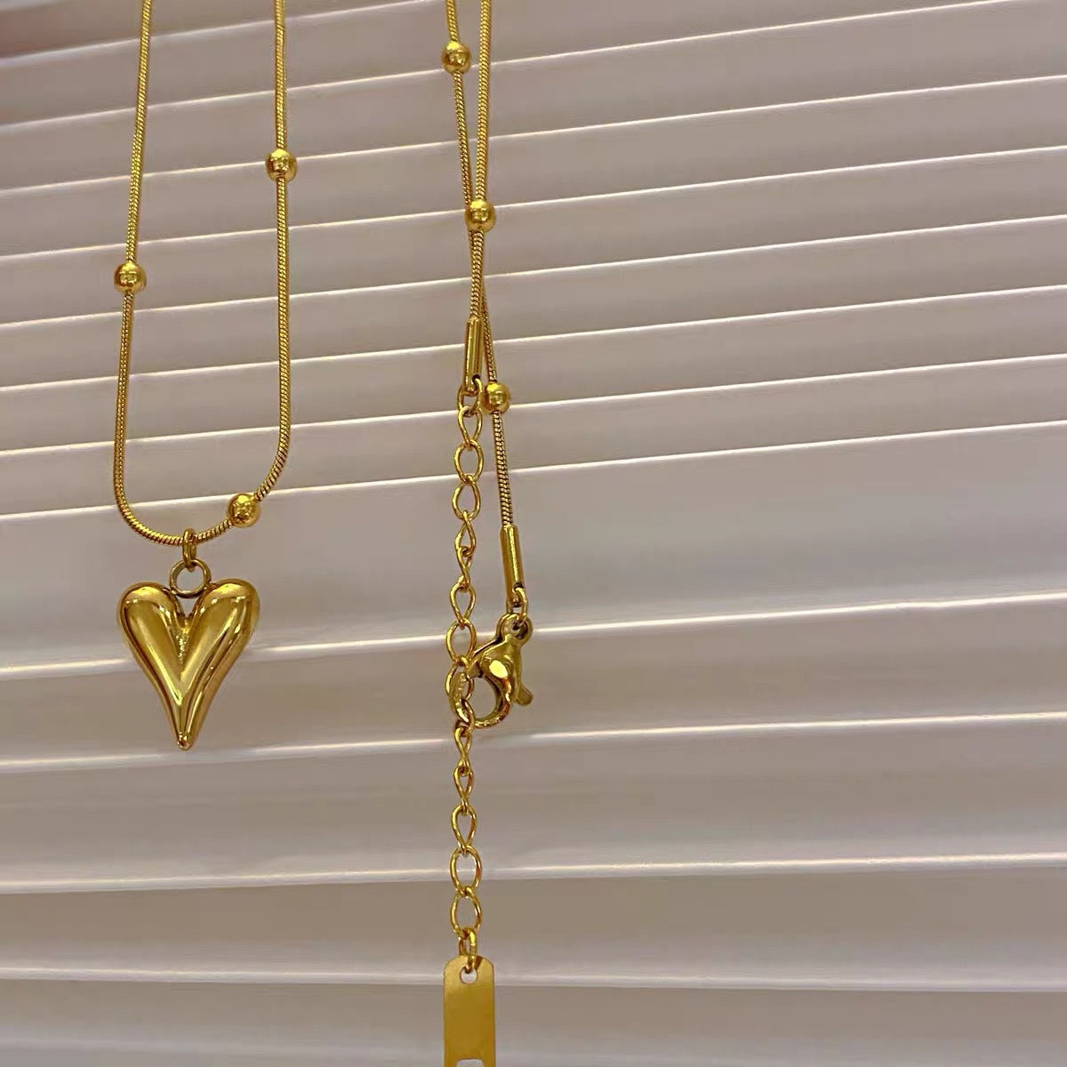 Detailed shot of the necklace clasp, $5\text{cm}$ extender, and the high-polish finish of the 3D heart pendant.