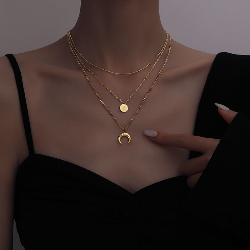 Frontal view of the celestial-themed triple-layer necklace with crescent moon and star motifs.