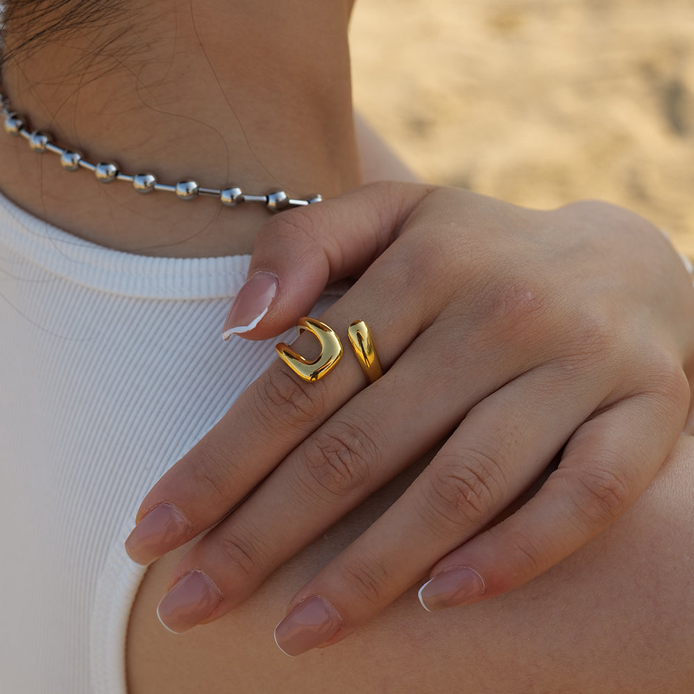 Lifestyle shot of a model wearing the gold organic open ring on her finger, styled with a white ribbed top.