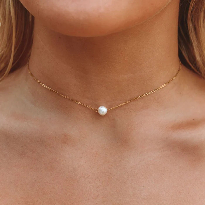 Macro view of the baroque pearl choker sitting perfectly on a model's collarbone.