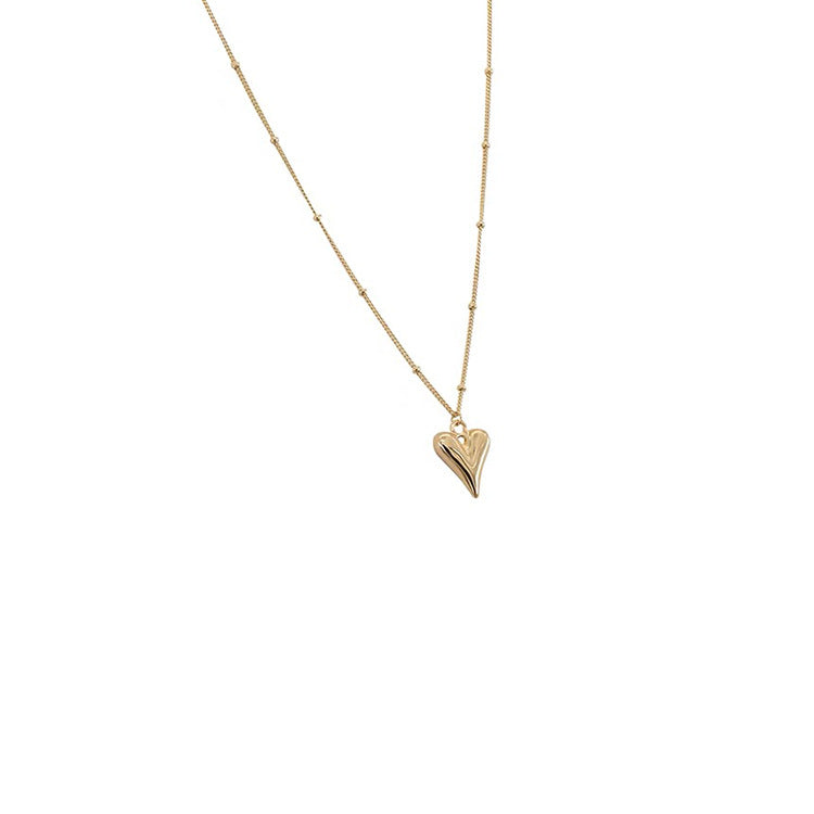 Minimalist studio shot of the gold heart pendant necklace on a clean white background, highlighting the satellite chain.