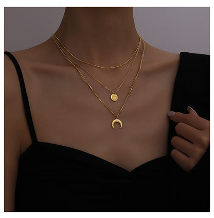 Professional model wearing a triple-layer gold celestial necklace with moon and star pendants against a black top.