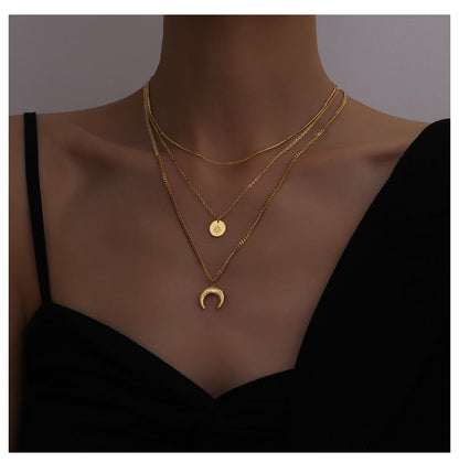 Studio portrait of a woman wearing the 18K gold PVD coated moon and star layered necklace.