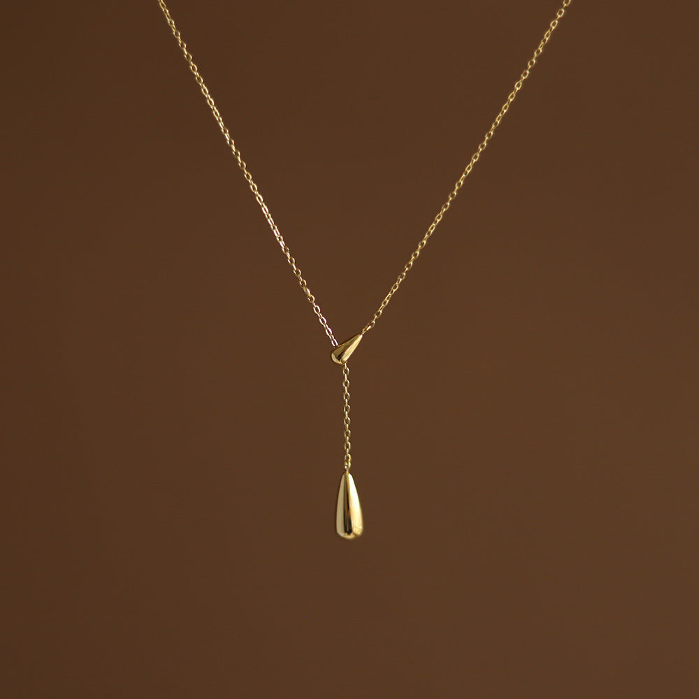 Studio portrait of the gold lariat necklace showing the elegant drop of the two teardrop pendants.