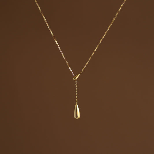 Studio portrait of the gold lariat necklace showing the elegant drop of the two teardrop pendants.