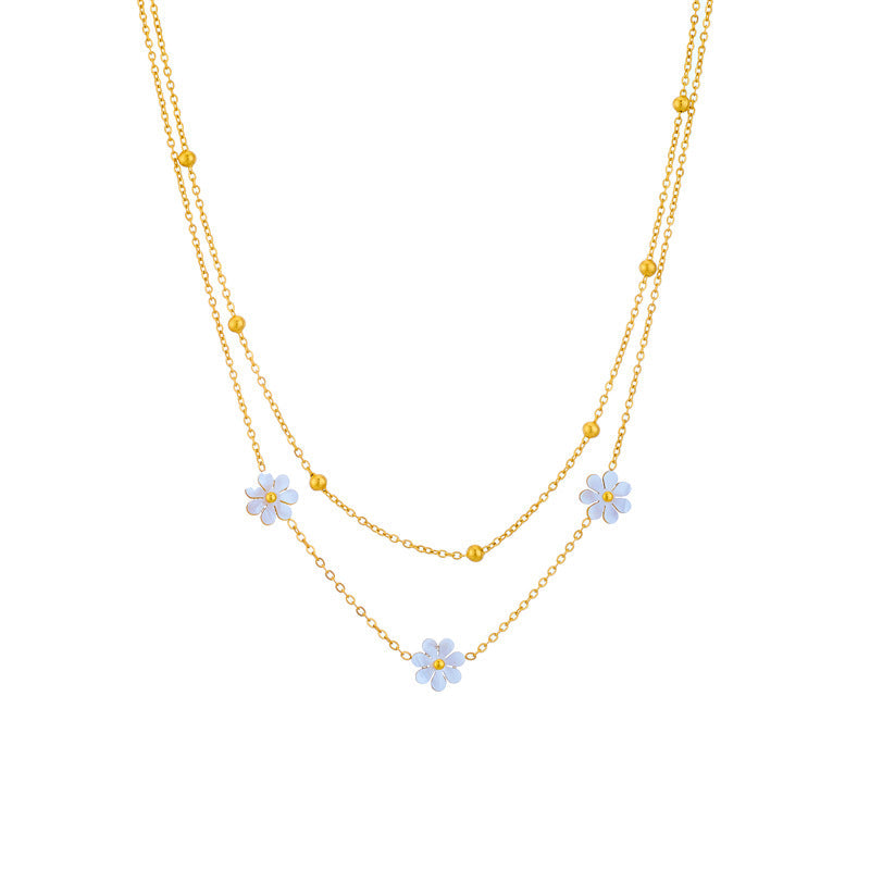 Studio shot of the 18K gold PVD plated double strand necklace with three white flower charms and gold bead accents.