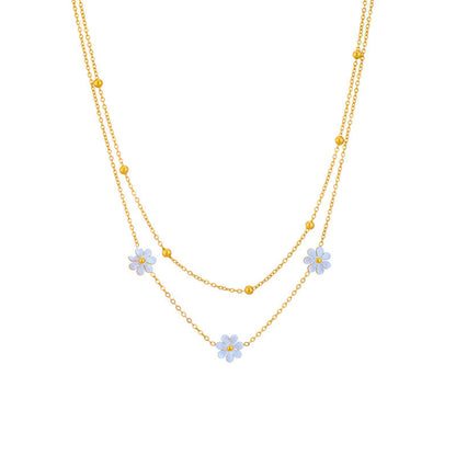 Studio shot of the 18K gold PVD plated double strand necklace with three white flower charms and gold bead accents.