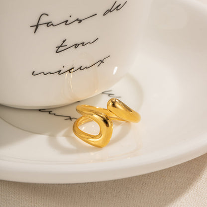 The gold-plated stainless steel open ring resting next to a white cup with French calligraphy.