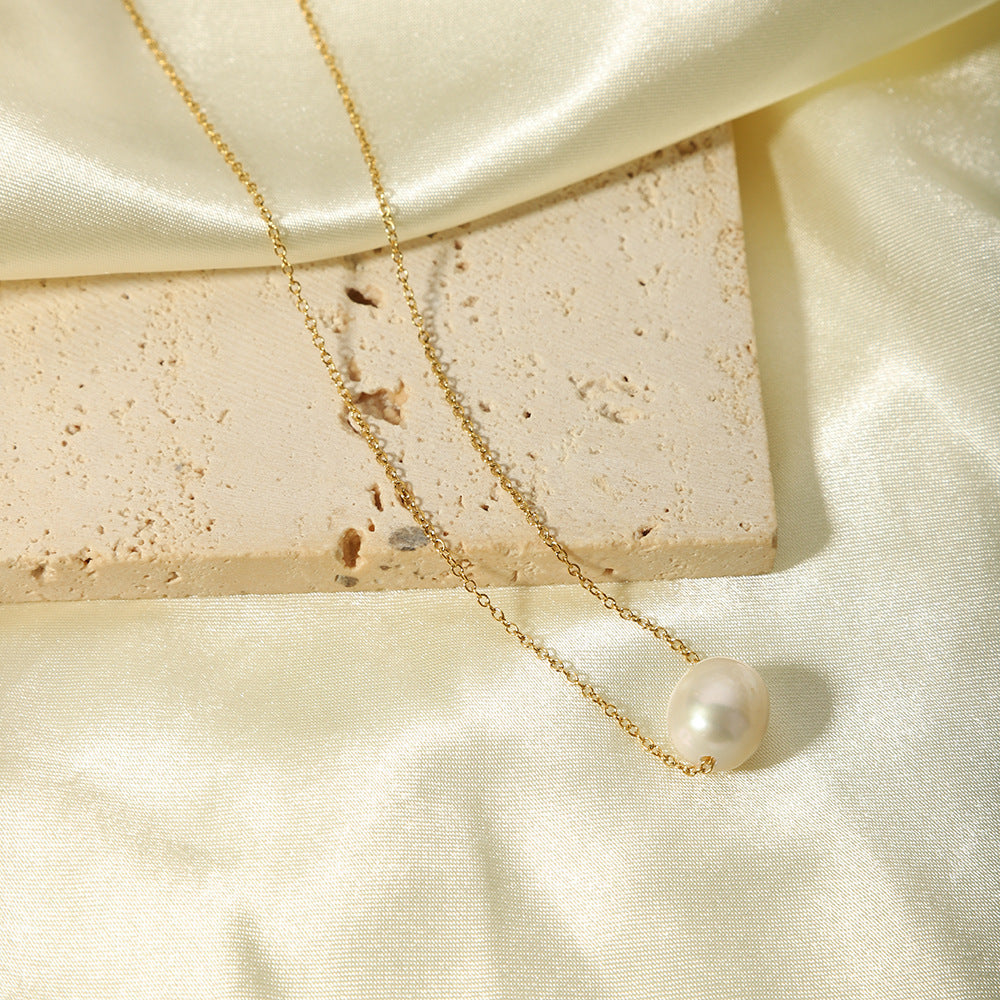 The tarnish-free gold pearl necklace displayed on a piece of white silk and a textured limestone block.