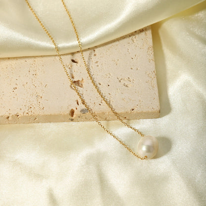 The tarnish-free gold pearl necklace displayed on a piece of white silk and a textured limestone block.