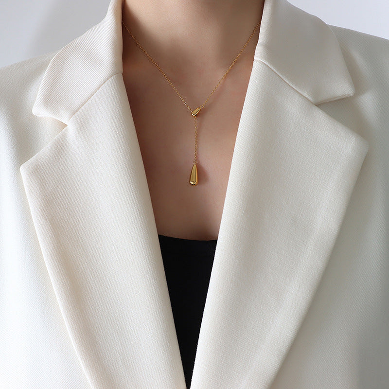 Professional model wearing the gold water droplet necklace with a crisp white blazer and black top.
