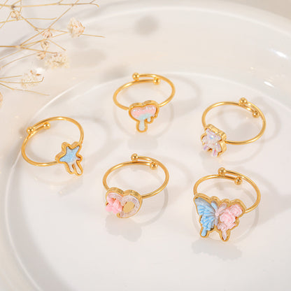 Top-down view of five different gold-plated resin rings arranged on a white ceramic plate, showcasing the variety of available designs.