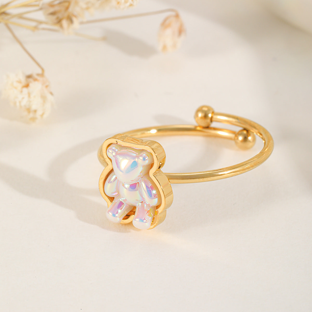 A cute gold adjustable ring featuring a translucent, iridescent gummy bear charm with a pearlescent finish.